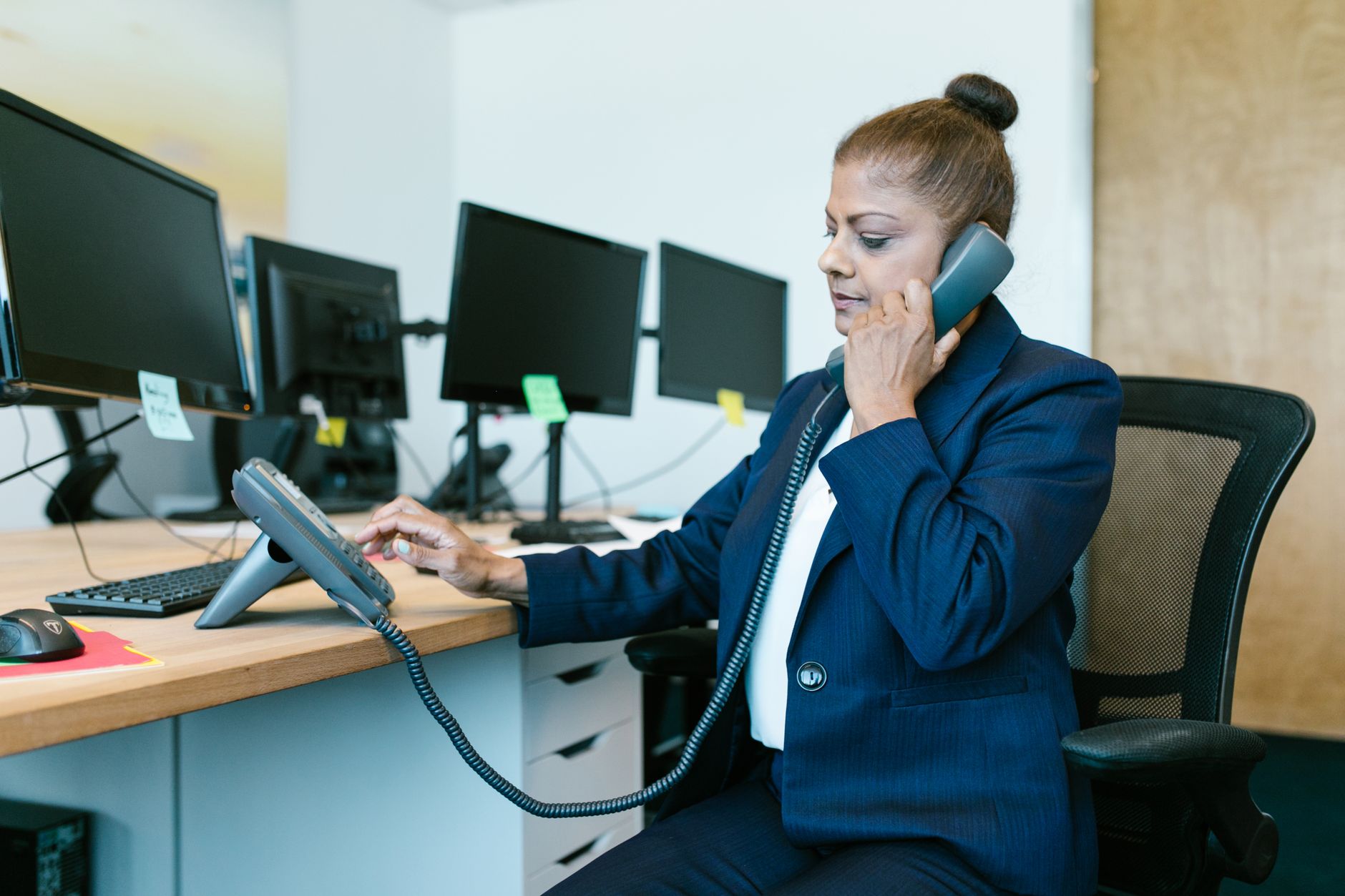 Assistante au téléphone à son bureau, devant plusieurs écrans
