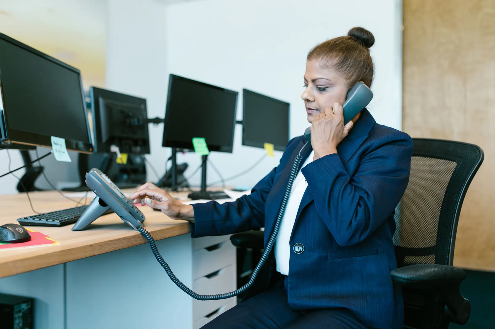 Assistante au téléphone à son bureau, devant plusieurs écrans