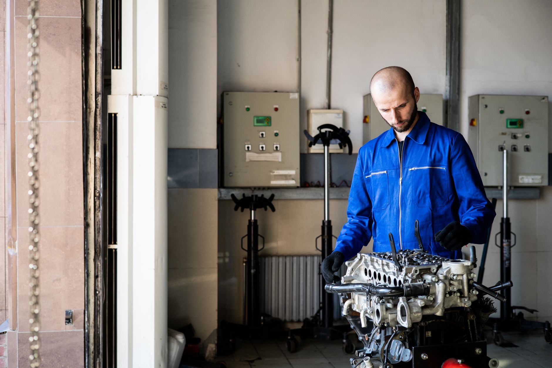 Mécanicien en bleu de travail penché sur un moteur dans un atelier de réparation