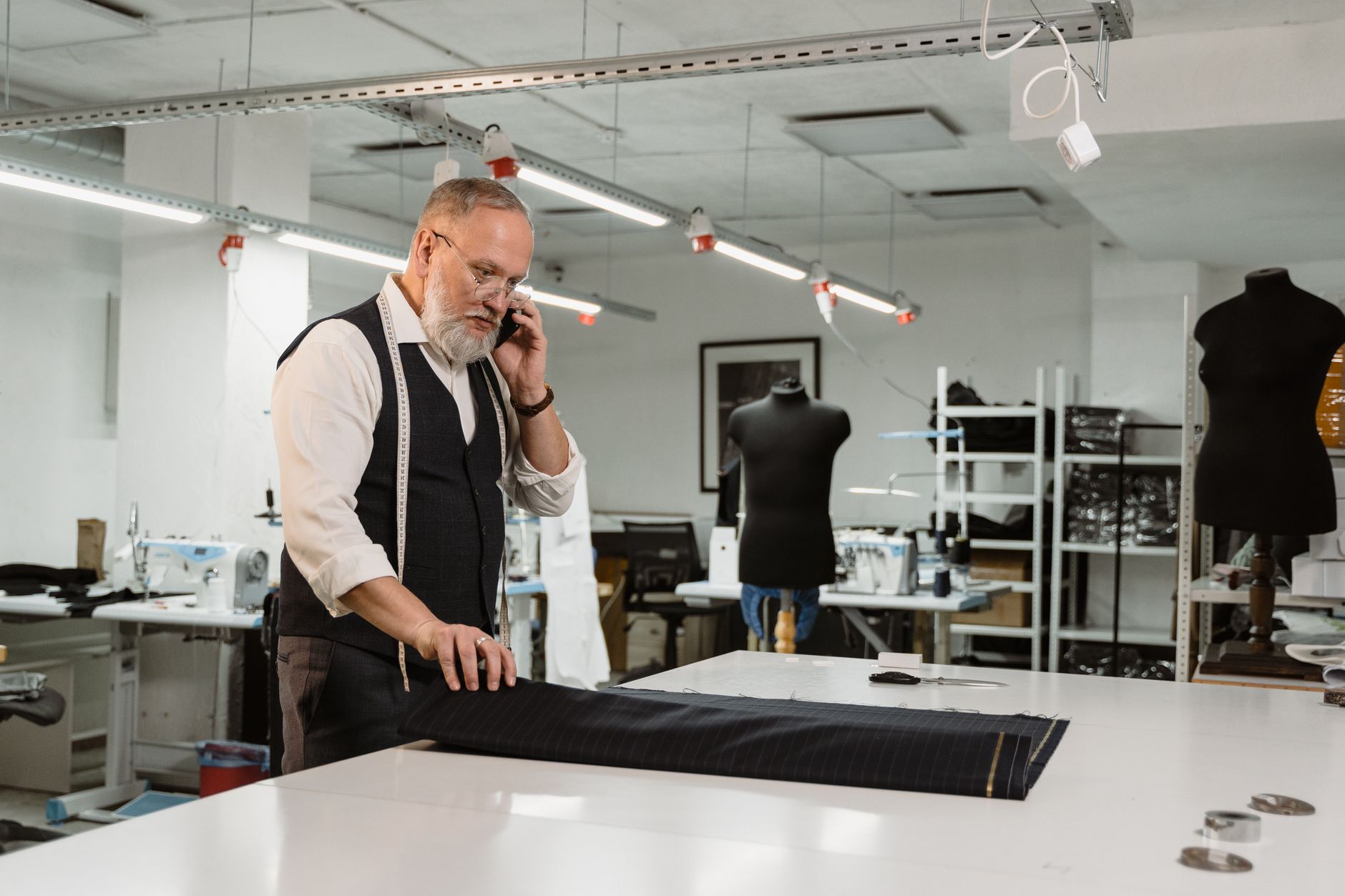 Artisan au téléphone dans son atelier, penché sur son plan de travail