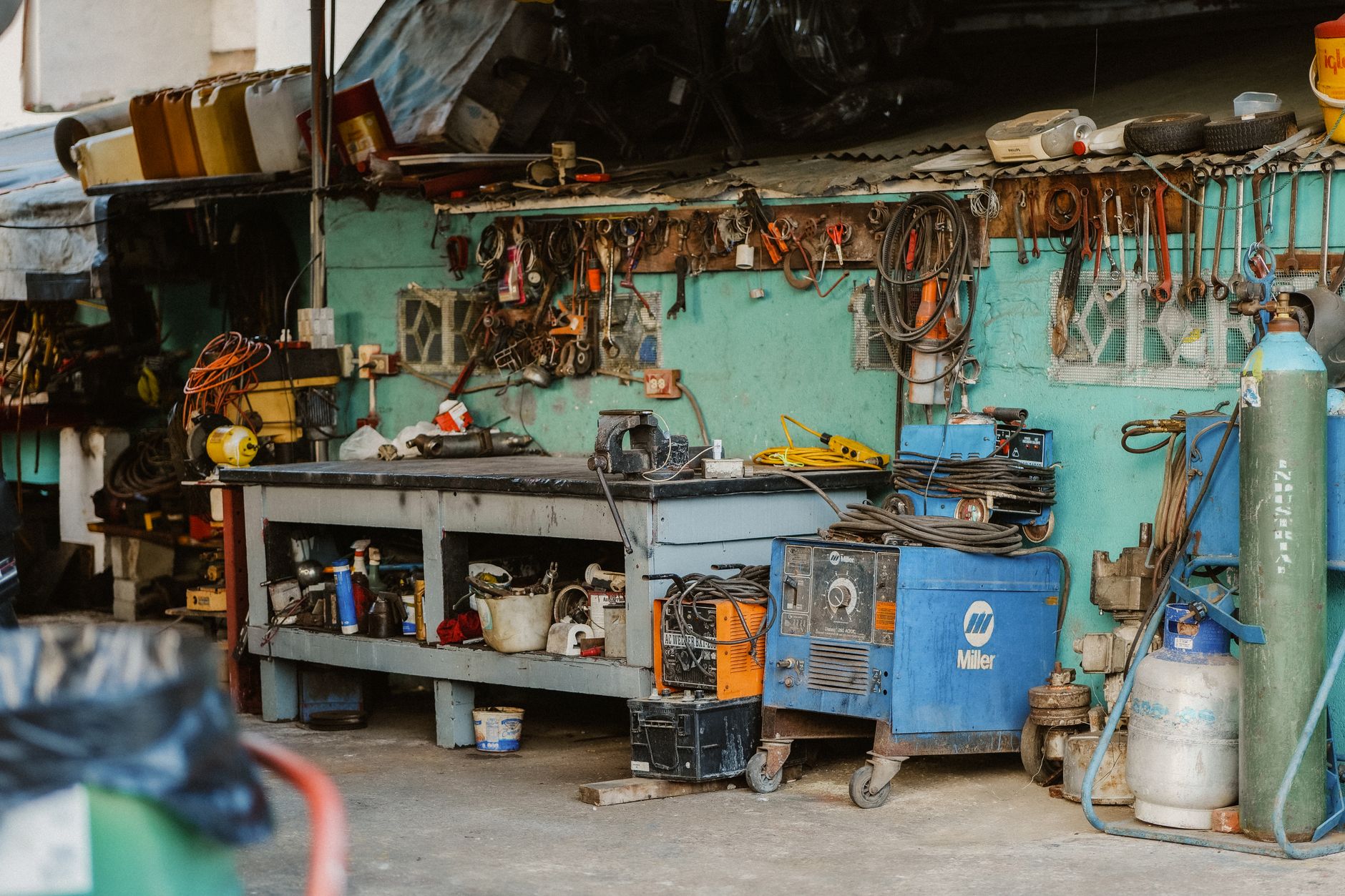 Établi d'atelier avec outillage suspendu, poste à souder et bouteilles de gaz