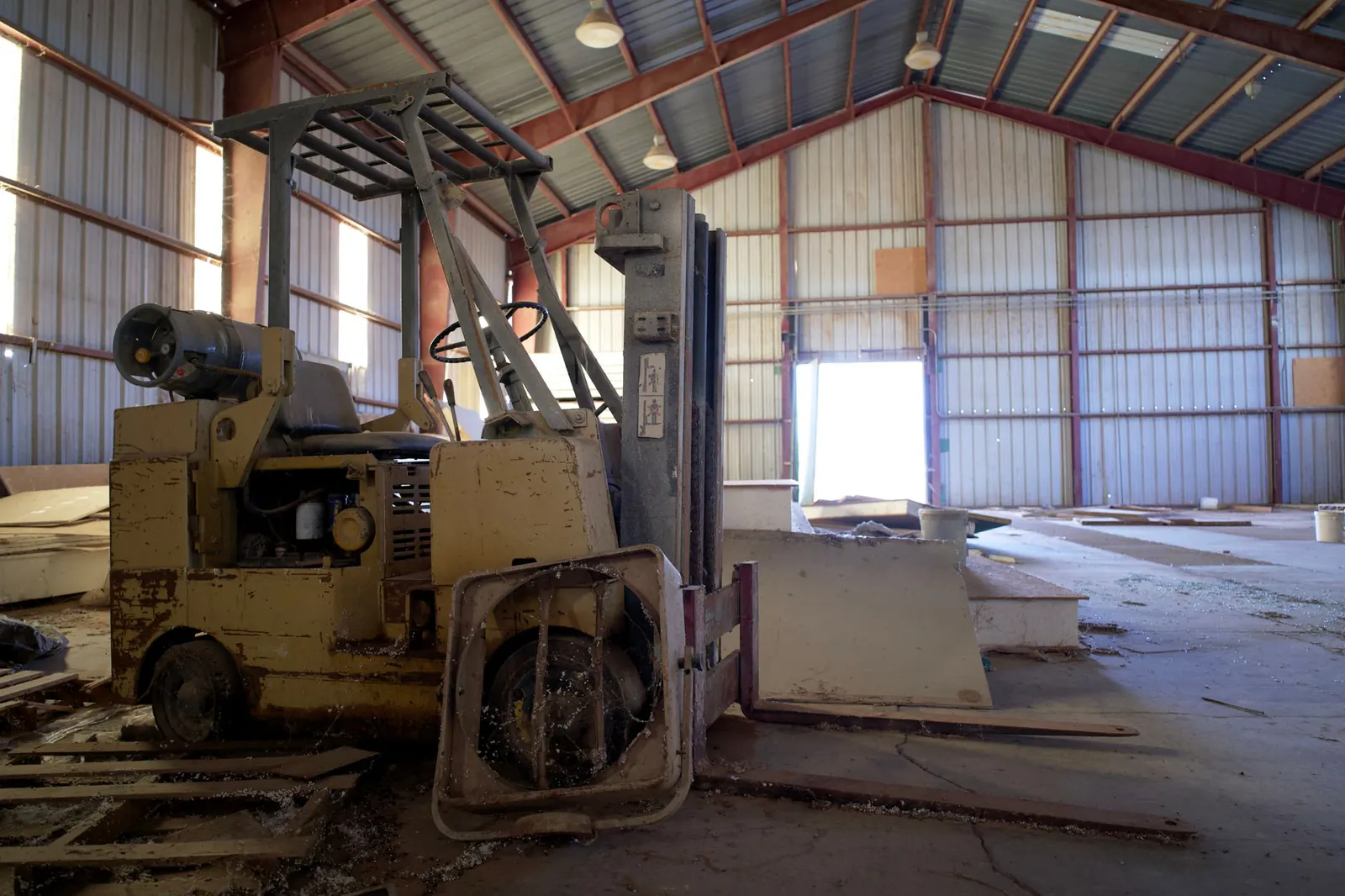 Vieux chariot élévateur jaune délabré dans un hangar abandonné à la tôle rouillée