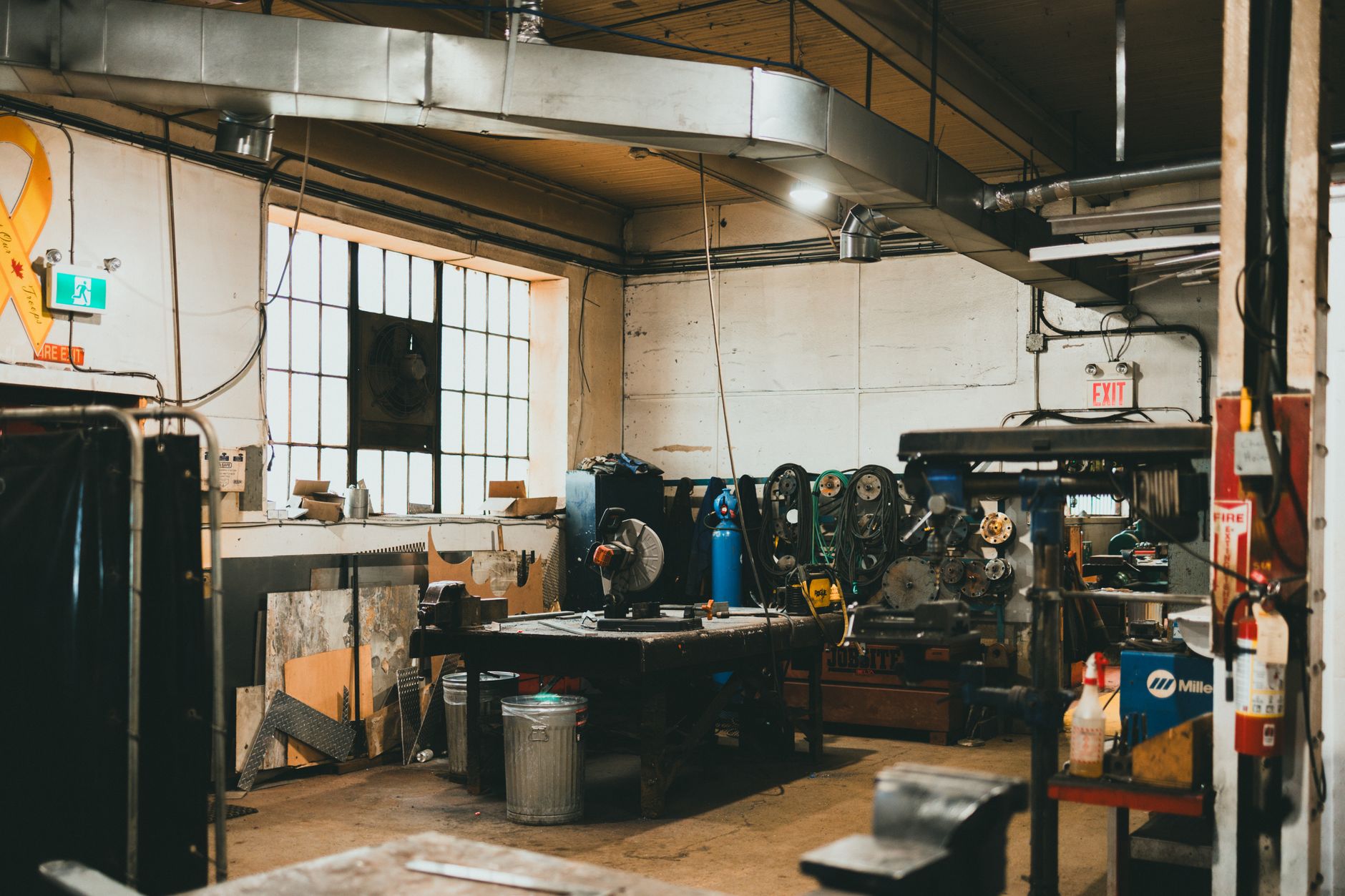 Atelier mécanique désert avec établis, machines-outils et lumière du jour par la fenêtre