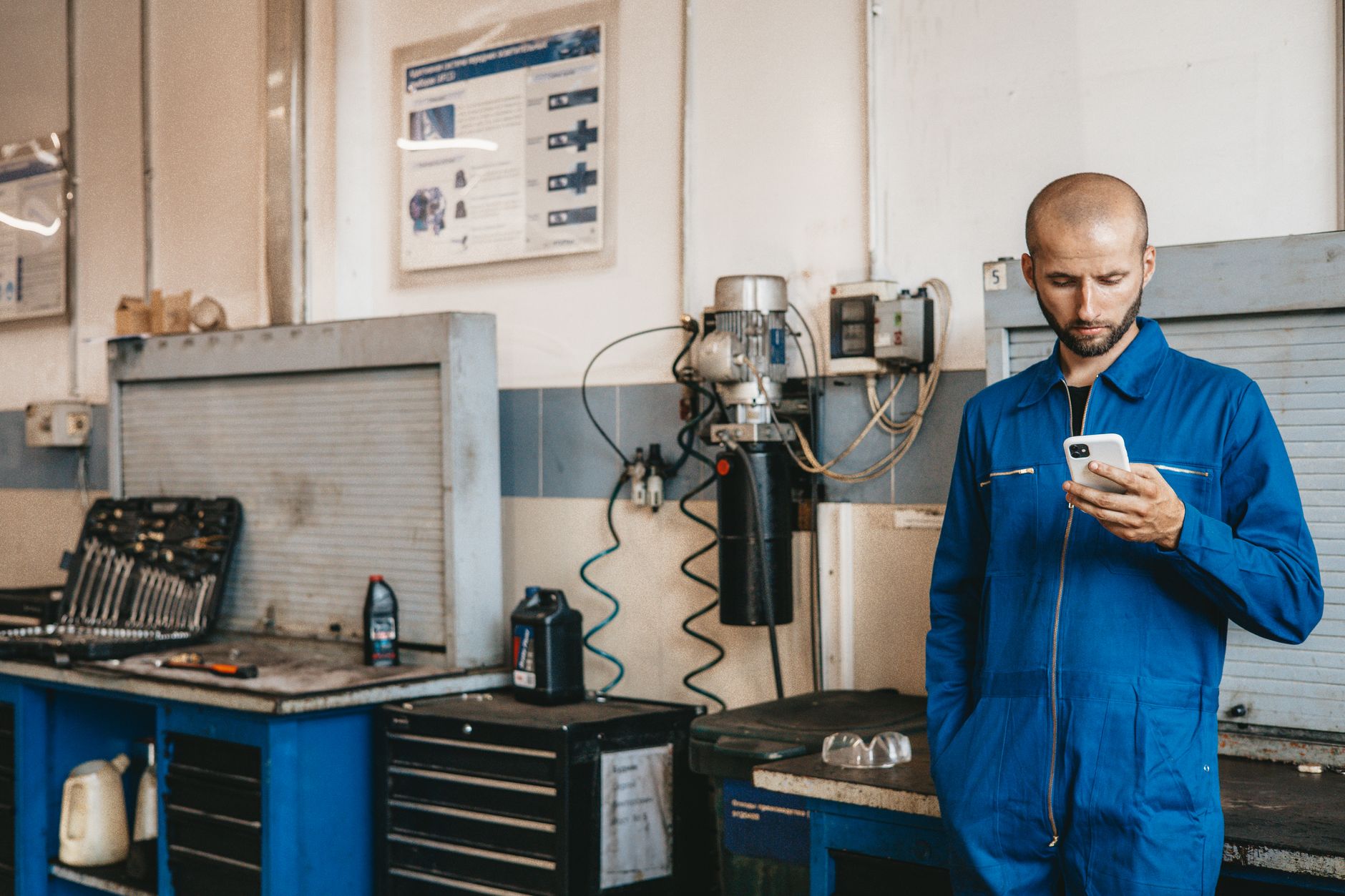 Technicien en bleu de travail consultant son téléphone dans un atelier de maintenance