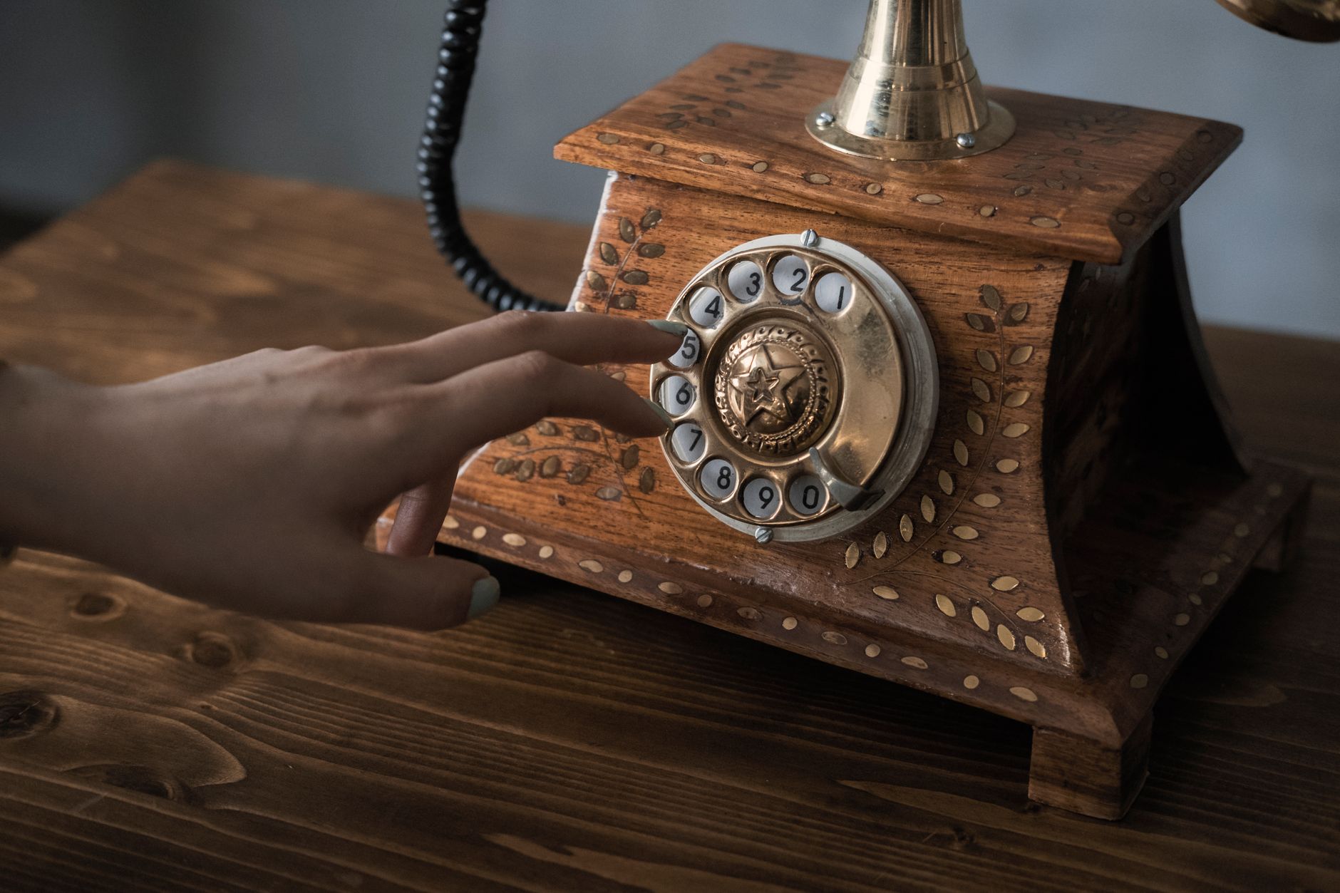 Main composant un numéro sur un ancien téléphone en bois à cadran rotatif